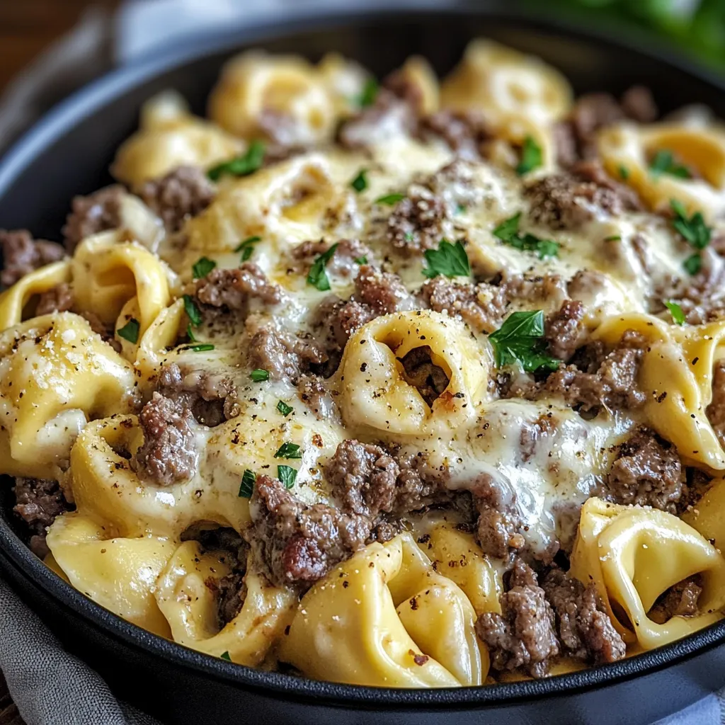 A skillet of Philly Cheesesteak Tortellini Pasta with melted cheese, tender beef, and colorful diced bell peppers, garnished with fresh parsley.