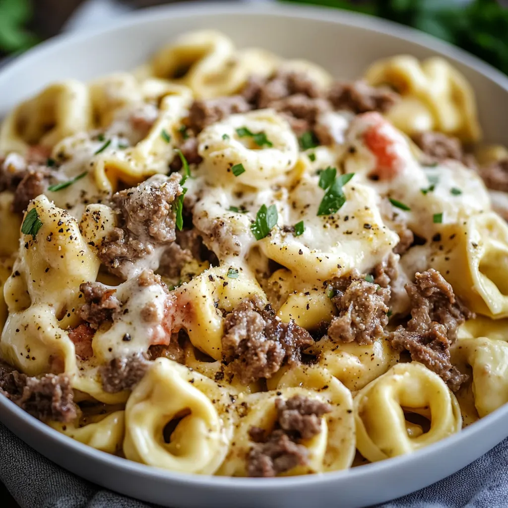 A skillet of Philly Cheesesteak Tortellini Pasta with melted cheese, tender beef, and colorful diced bell peppers, garnished with fresh parsley.