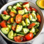 Fresh Tomato, Cucumber, and Avocado Salad garnished with parsley and served in a white bowl.