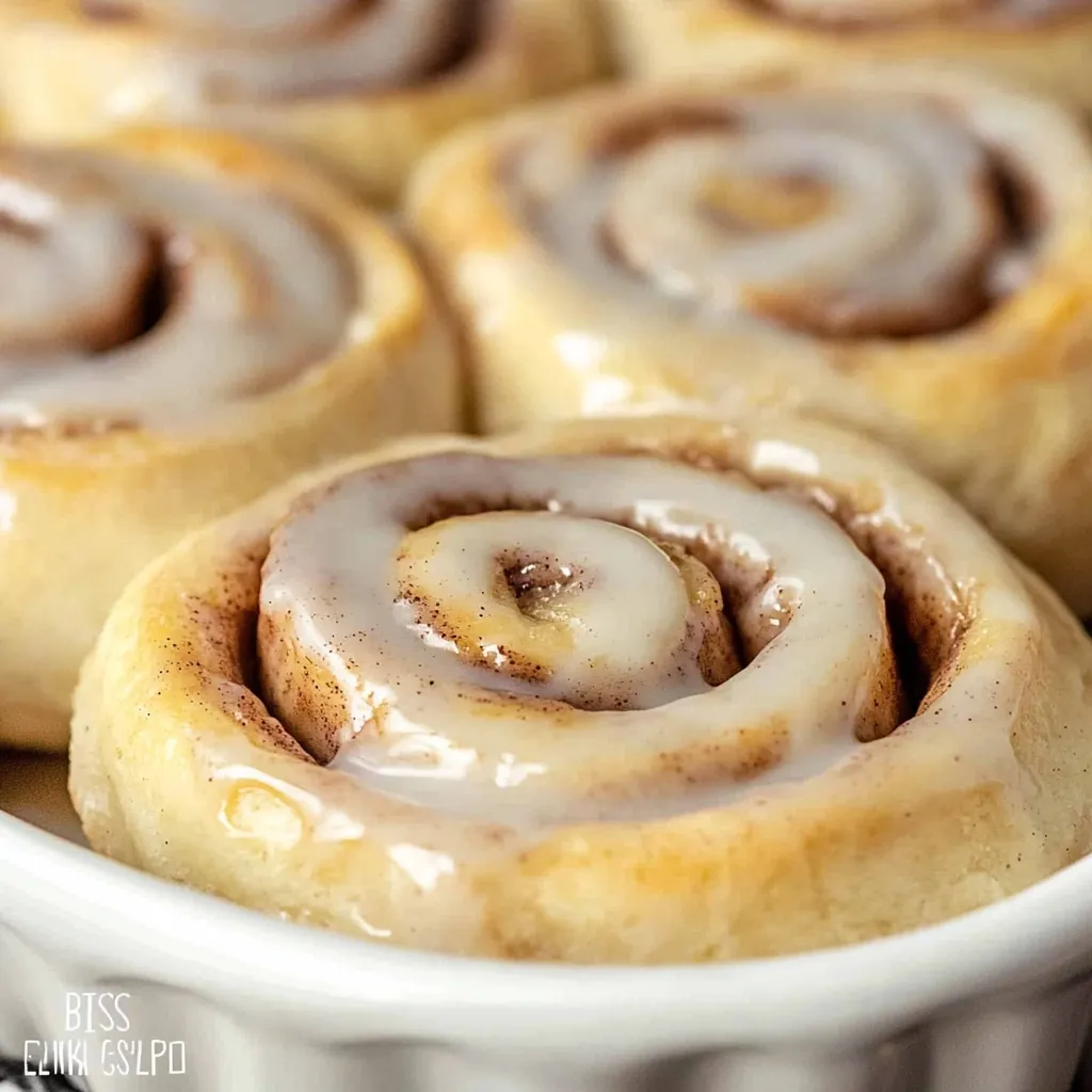 Golden brown Bisquick Cinnamon Rolls drizzled with a sweet vanilla glaze, served on a decorative platter.