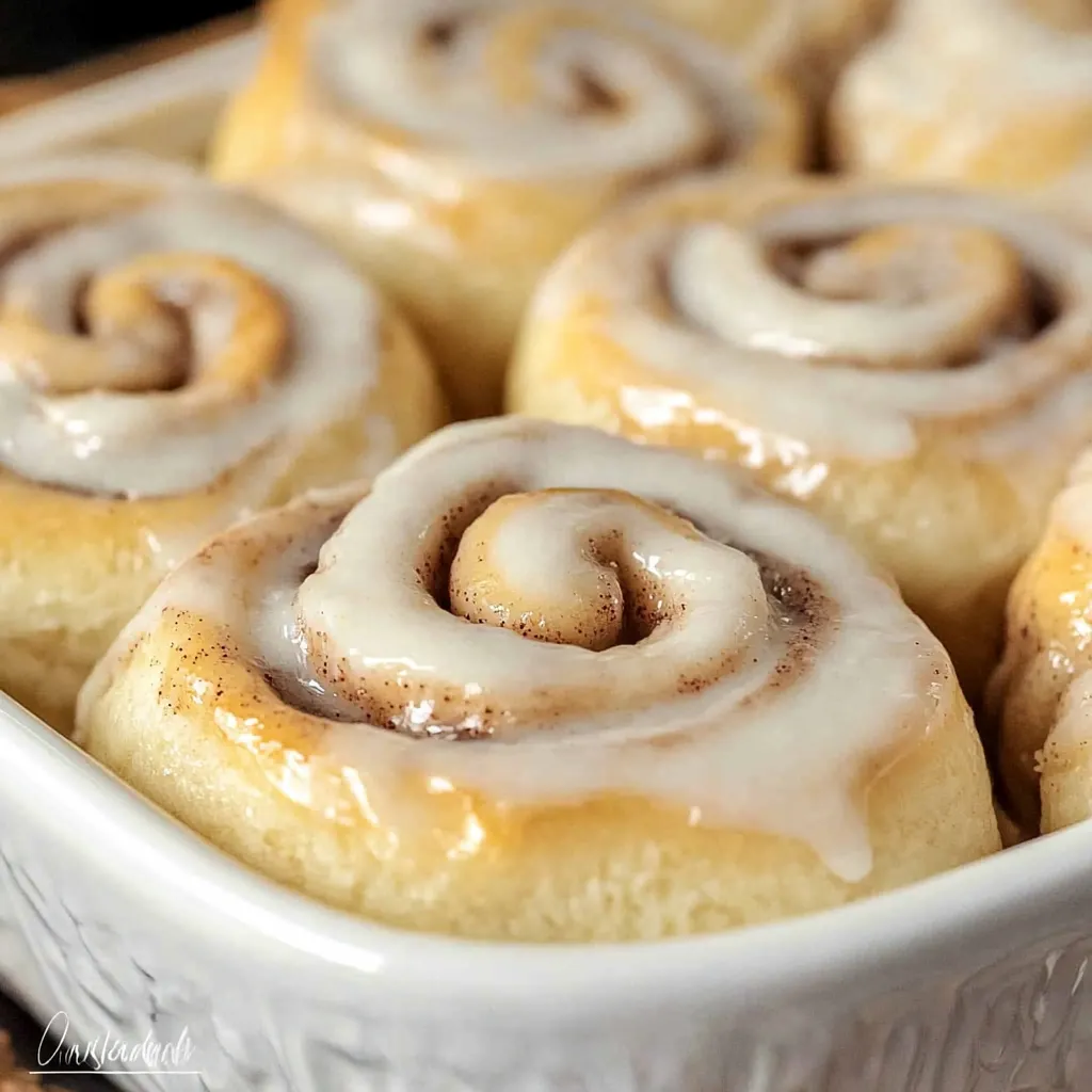 Golden brown Bisquick Cinnamon Rolls drizzled with a sweet vanilla glaze, served on a decorative platter.