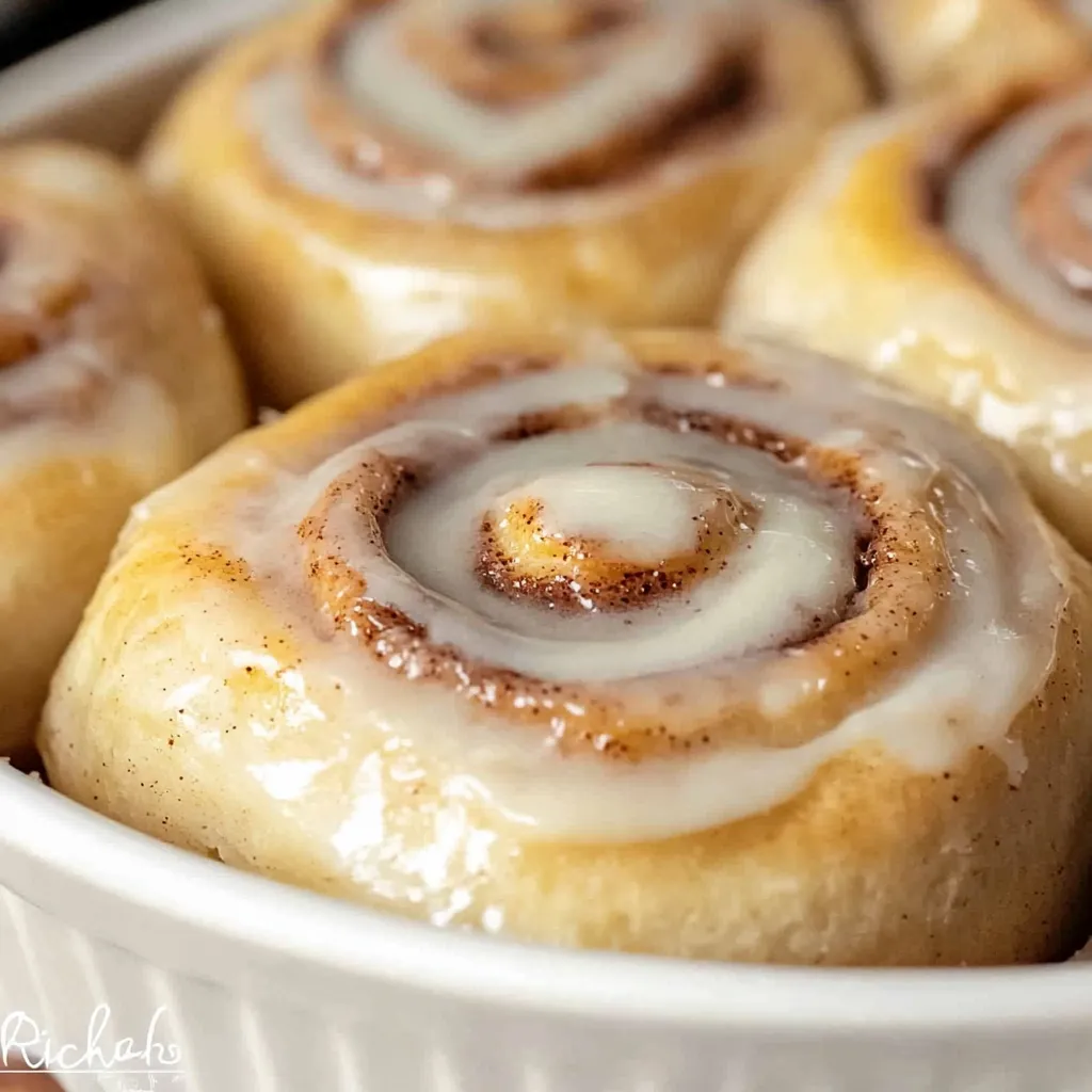 Golden brown Bisquick Cinnamon Rolls drizzled with a sweet vanilla glaze, served on a decorative platter.