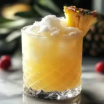 A glass of Snowy Pineapple Punch garnished with a pineapple wedge and sprinkled with shredded coconut, served with a colorful straw.