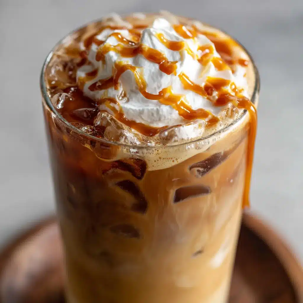 A glass of caramel iced coffee topped with whipped cream and caramel drizzle.