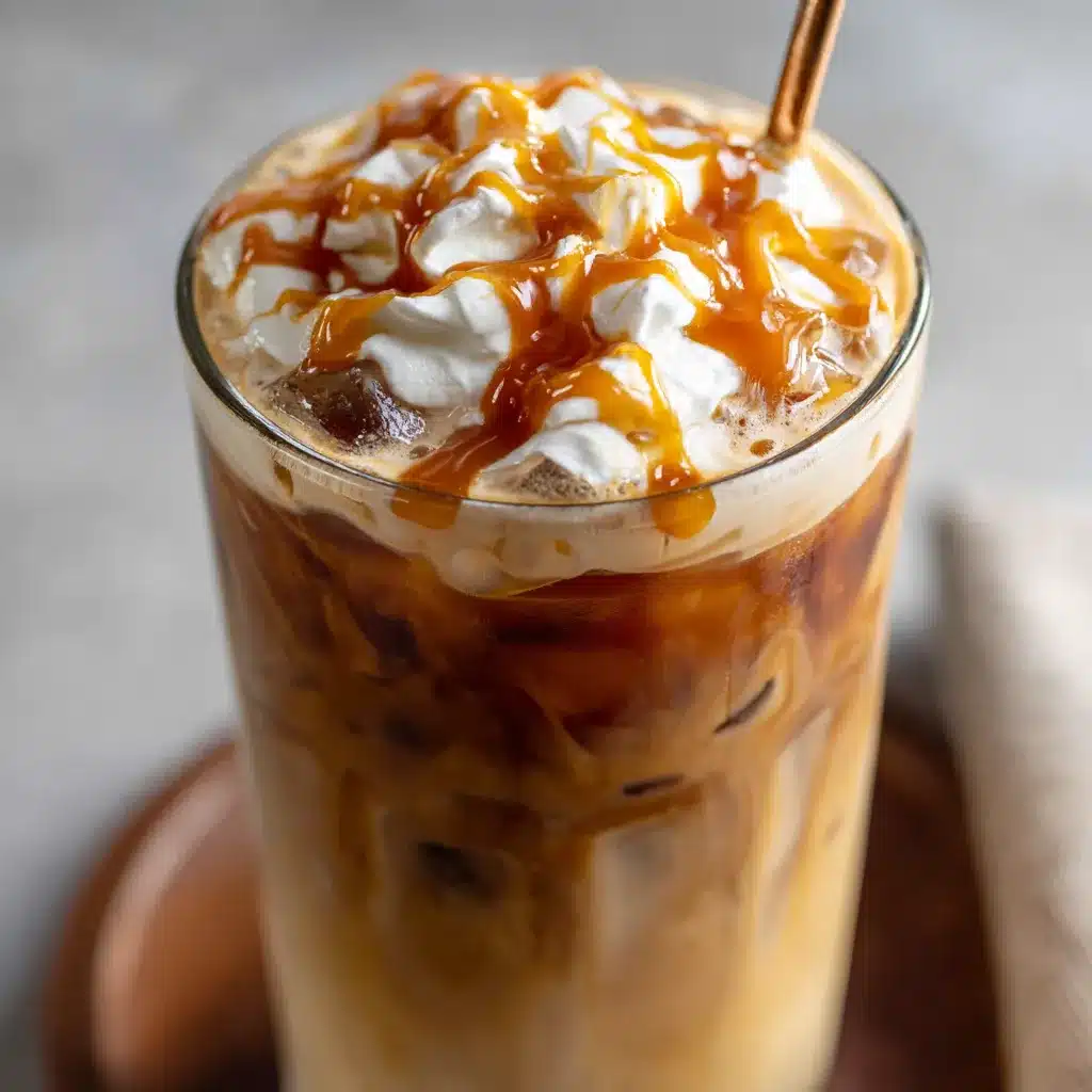 A glass of caramel iced coffee topped with whipped cream and caramel drizzle.