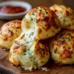 Gooey Mozzarella Biscuit Bombs served warm with marinara dipping sauce on a rustic plate.