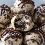 Close-up of chocolate-dipped Oreo cookie dough bites on a parchment-lined tray.