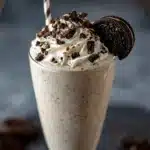 Creamy Boozy Baileys Oreo Milkshake in a frosted glass topped with whipped cream, chocolate drizzle, and crushed Oreos.