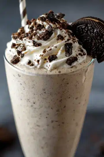 Creamy Boozy Baileys Oreo Milkshake in a frosted glass topped with whipped cream, chocolate drizzle, and crushed Oreos.