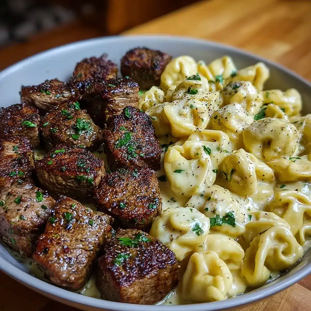 Creamy garlic butter steak bites served with tortellini in Alfredo sauce in a white skillet.