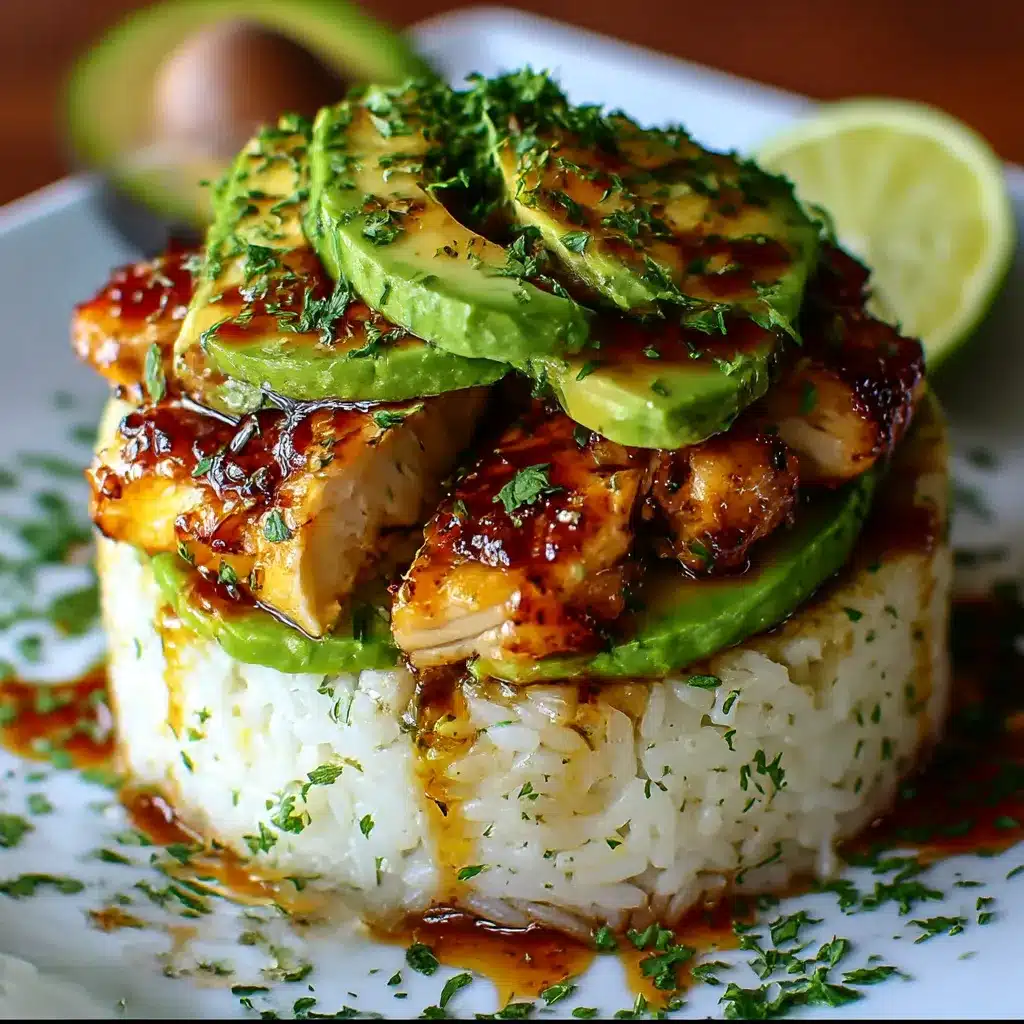 Honey lime chicken and avocado rice stack served on a plate, topped with lime wedges and fresh cilantro.