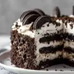 Slice of creamy No-Bake Oreo Cake topped with mini Oreos on a white plate.