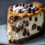 Slice of chocolate chip cookie cheesecake with melted mini chocolate chips and cookie crumb topping