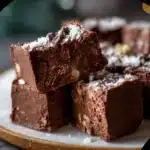 A batch of healthy no-bake cottage cheese chocolate fudge cut into small squares on parchment paper.