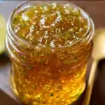 Lemon Zest Jalapeño Shine Jelly in a glass jar with fresh lemons and sliced jalapeños