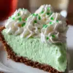 Slice of bright green Shamrock Shake Pie with whipped cream and chocolate shavings